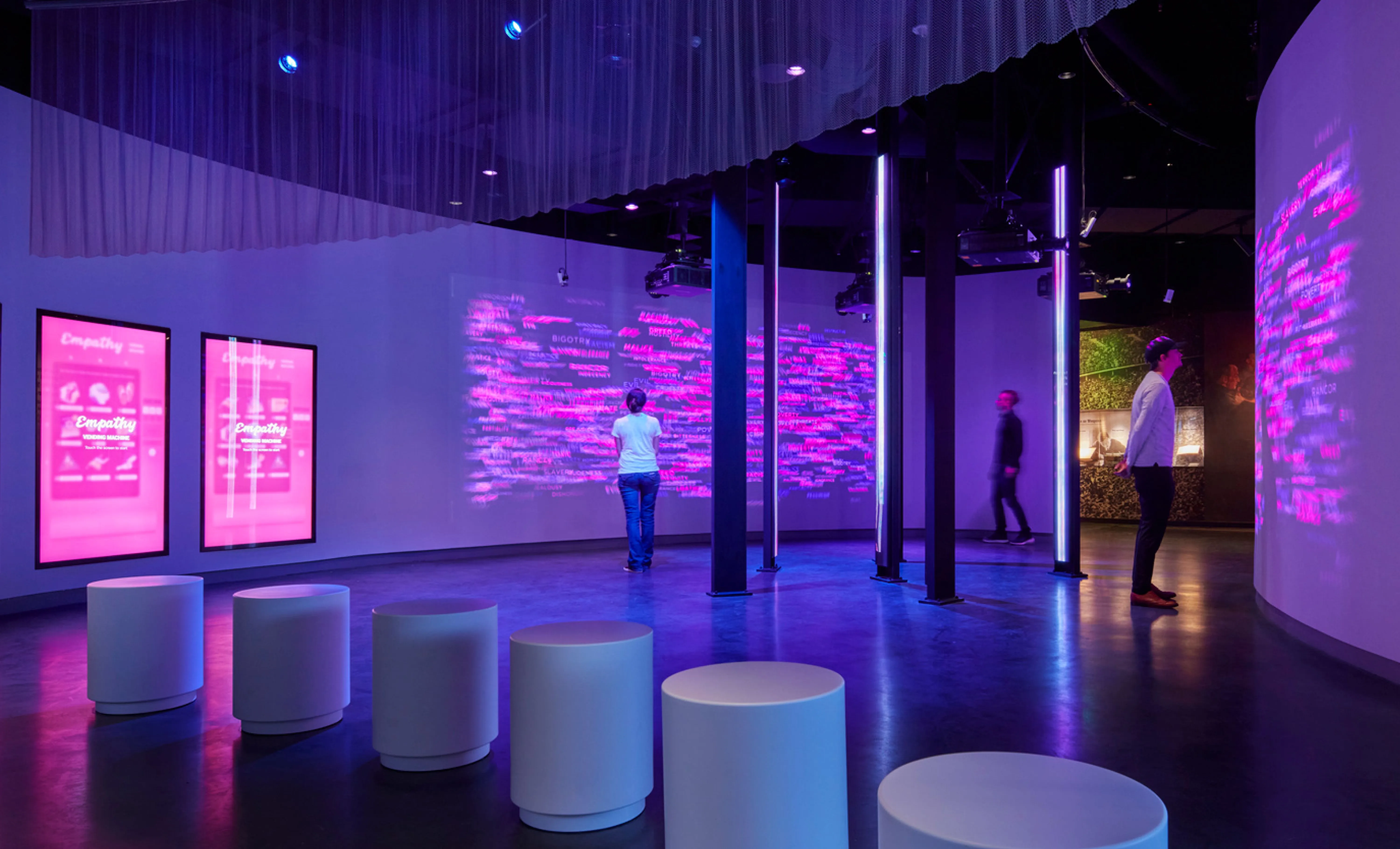 Visitors stand around a wall projection after interacting with Empathy Vending Machine.
